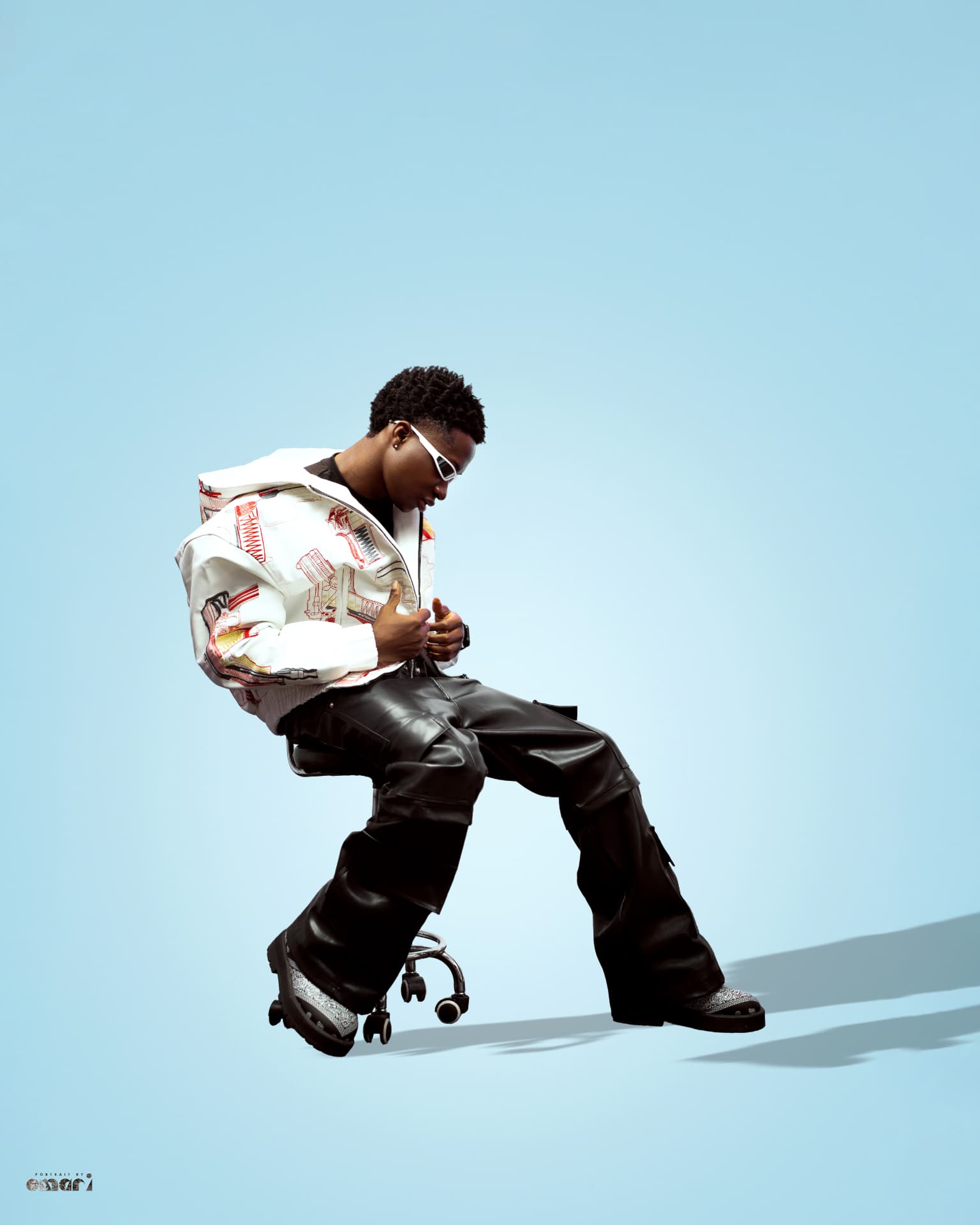 Boyyana seated on a stool adjusting his jacket