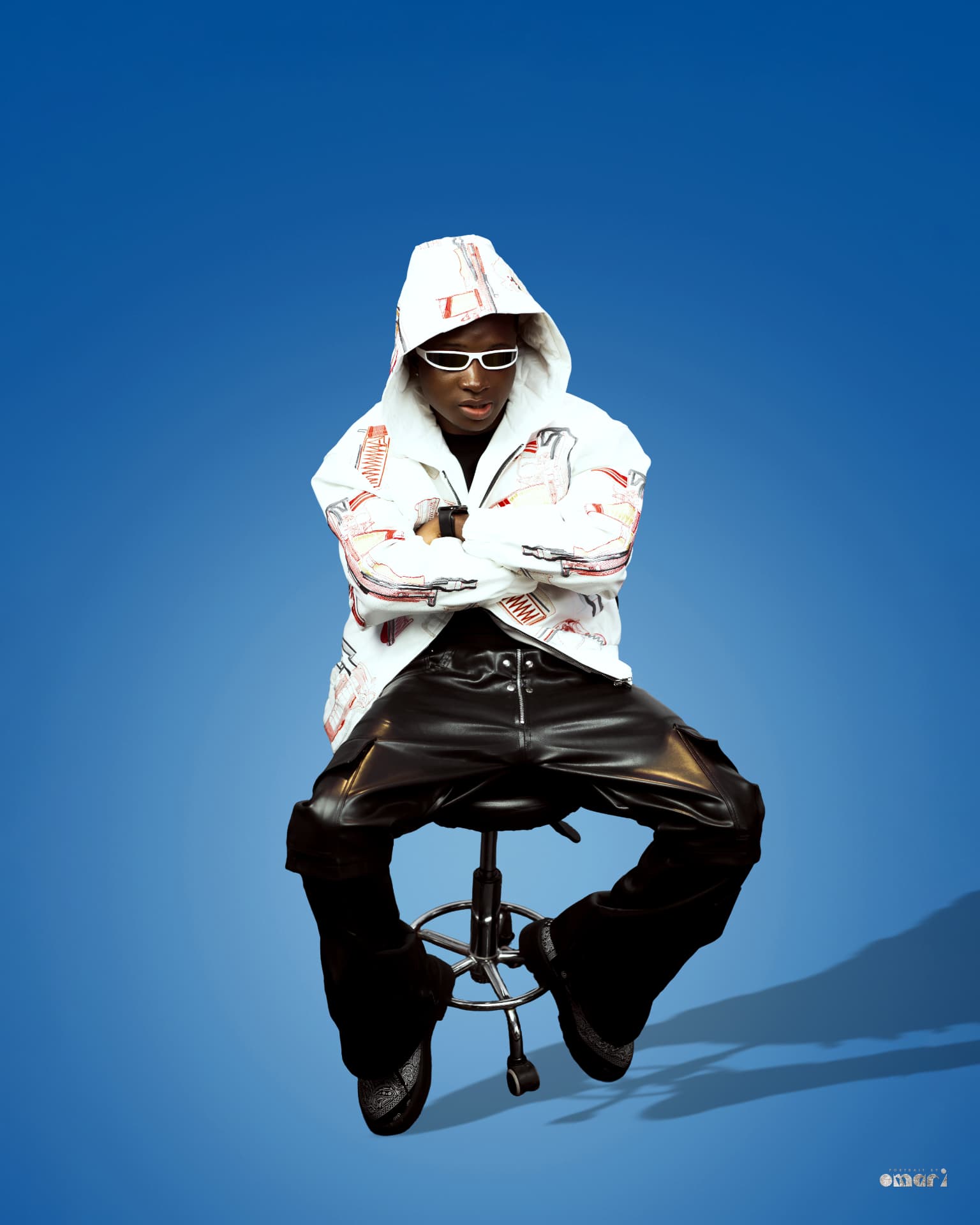 Boyyana seated with arms crossed, hood up