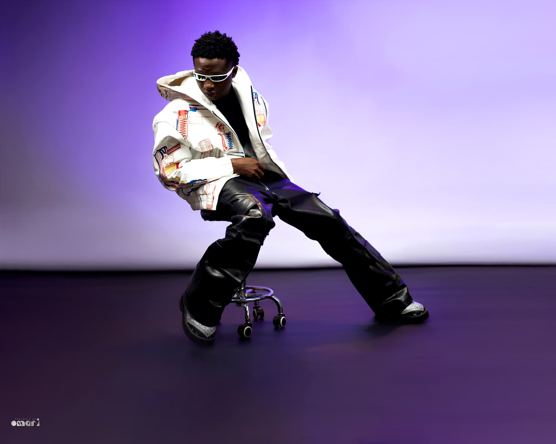 Boyyana seated on a rolling stool in purple studio light